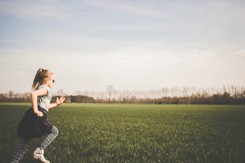 a little girl wearing striped leggings and boots running in a grassy field in germany, germany field runs 4k
