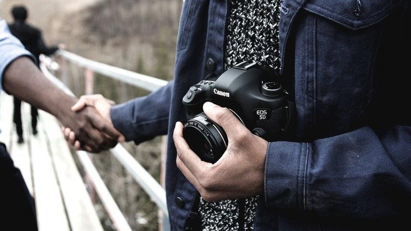photographer in edmonton holding a canon 5d dslr camera giving a handshake to another man, friendly edmonton photographer 4k