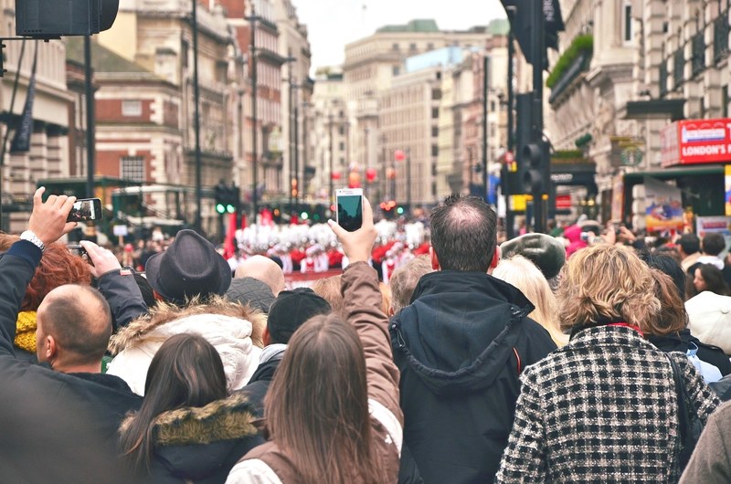 a crowd of people filming a parade in piccadilly circus with their smartphones, parade in london 4k