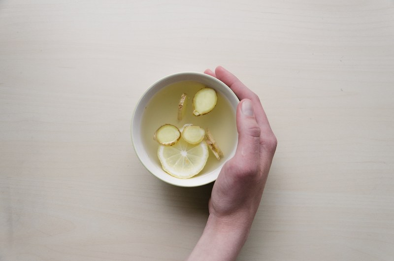 hand holds a bowl of broth with lemon and ginger health soup, detox remedies 4k