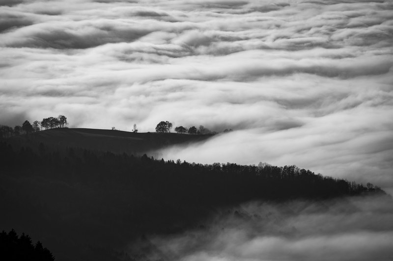 a desaturated shot of clouds enveloping hills in the countryside, cloudy rural hills 4k