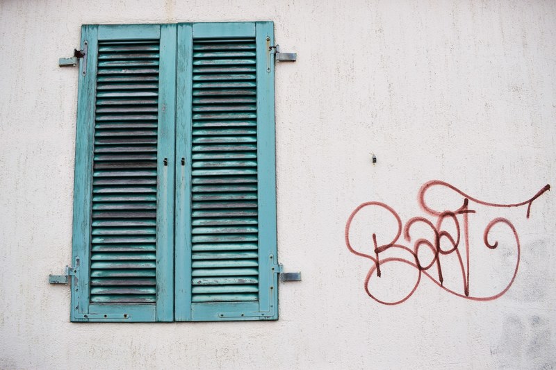 red graffiti tag on white wall next to worn green window shutter, graffiti and window shutter 4k