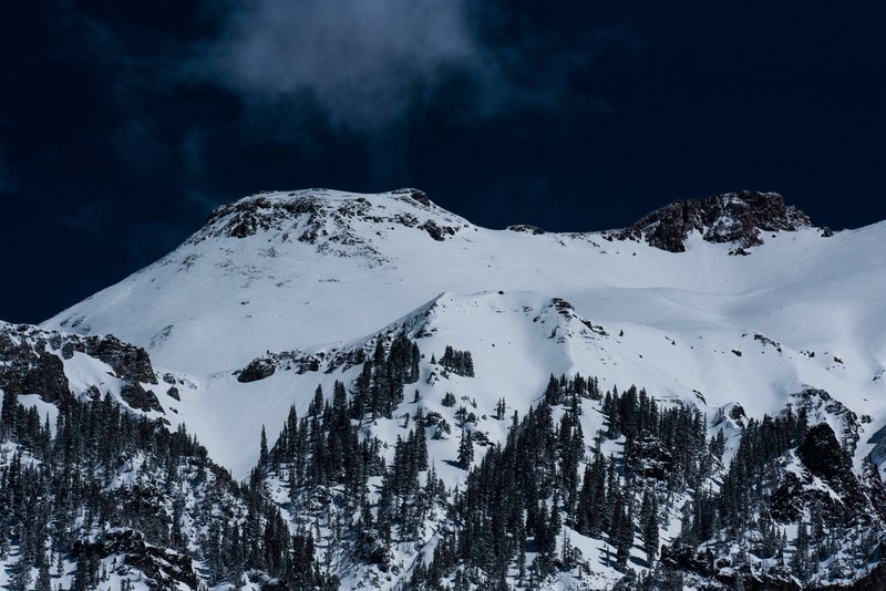 a tall snow covered mountain under a dark evening sky, mountain in ouray in the evening 4k