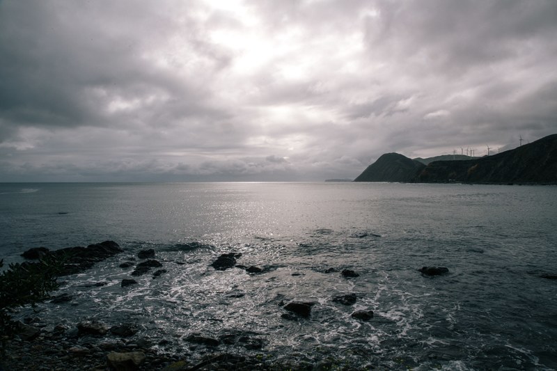 view of the ocean horizon with windmills on the coastline on a cloudy day at makara beach, ocean horizon view 4k