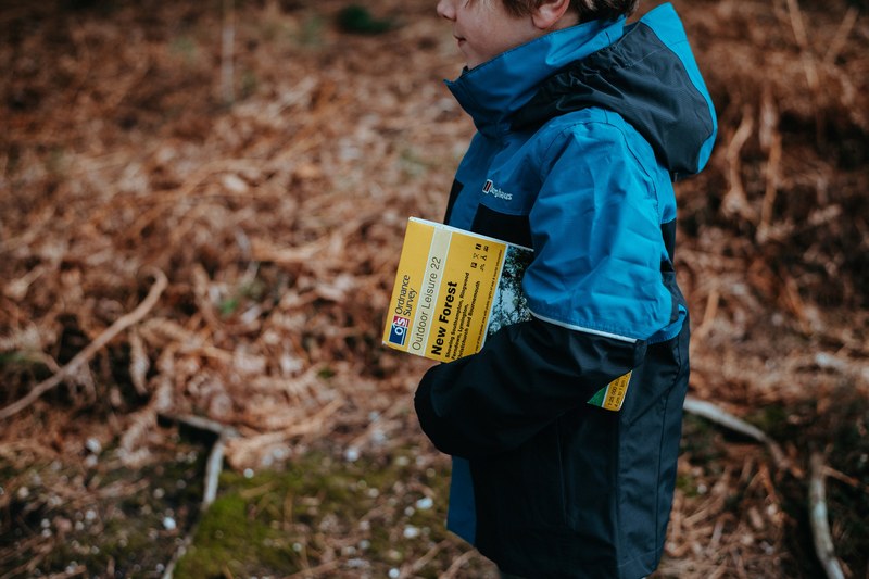 a child with a guidebook under his arm in a forest, new forest mapping 4k