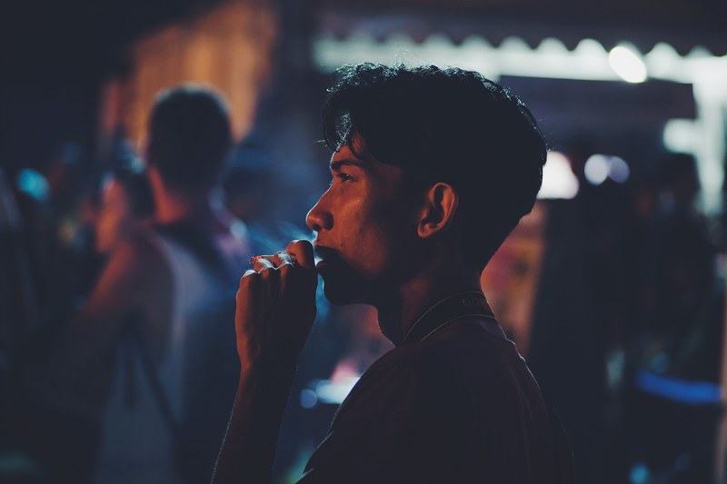 man smoking in crowded kuta city street, man smoking in kuta 4k