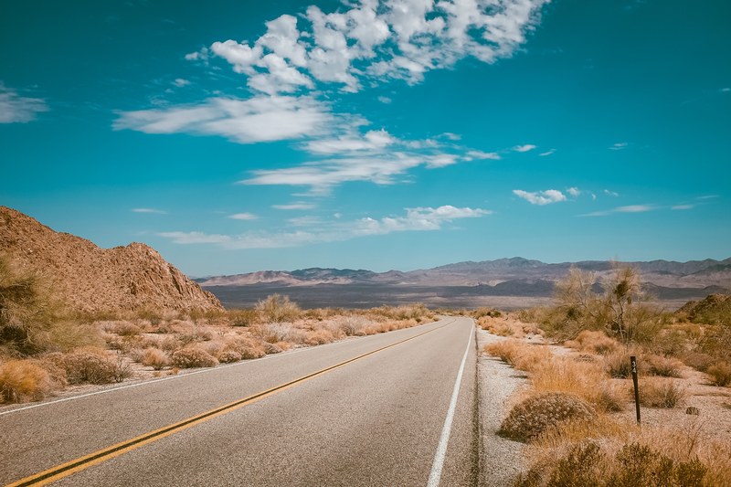 empty highway across the desert with blue sky and mountains in the background, desert empty highway 4k