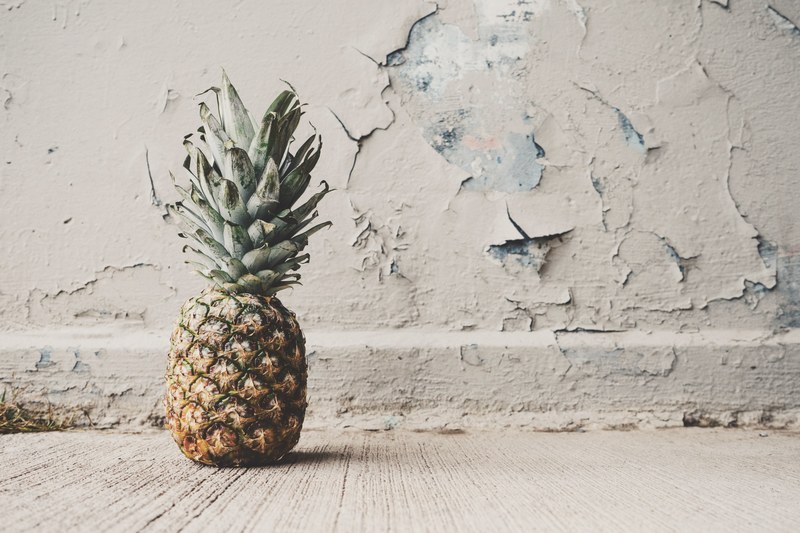 single fresh pineapple in an abandoned room with peeling paint, pineapple on the floor 4k