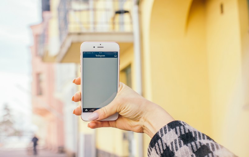 a woman holding an iphone with the instagram app open in a street, instagram in the street 4k