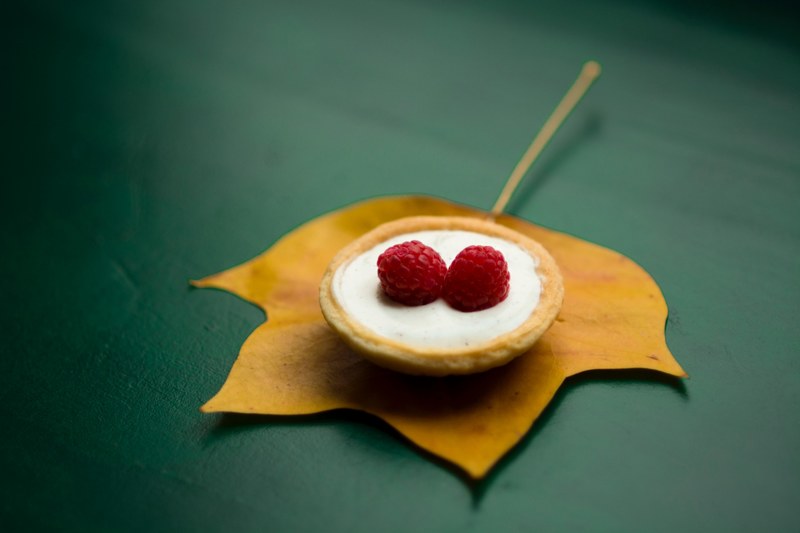 raspberry pastry on an orangish yellow leaf on a green table, autumn desserts 4k