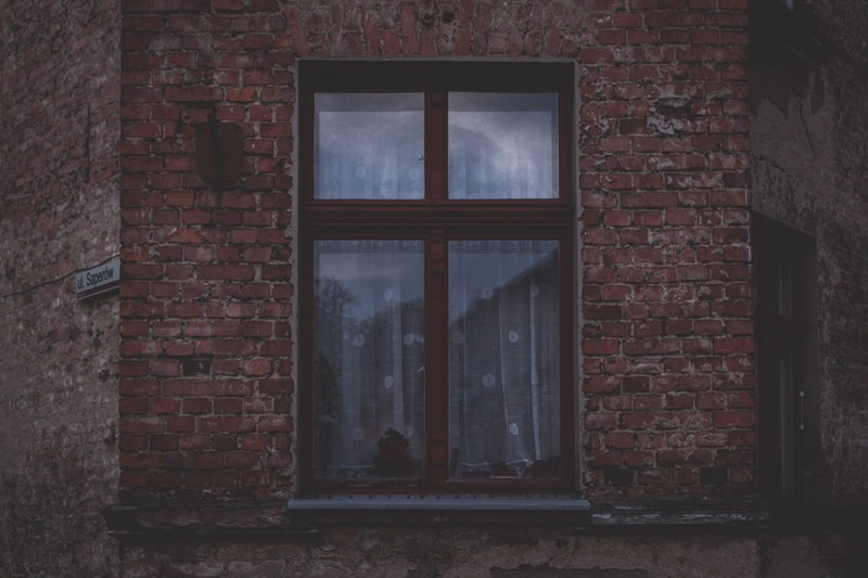 brick wall with a square window in the center reflecting an urban setting of other brick buildings, brick and square window 4k
