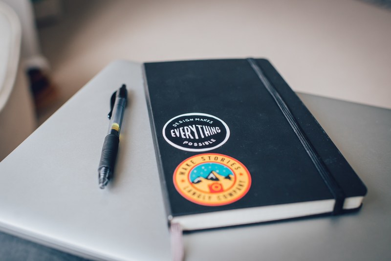 a pen next to a notebook with two stickers, stickers on a notebook 4k