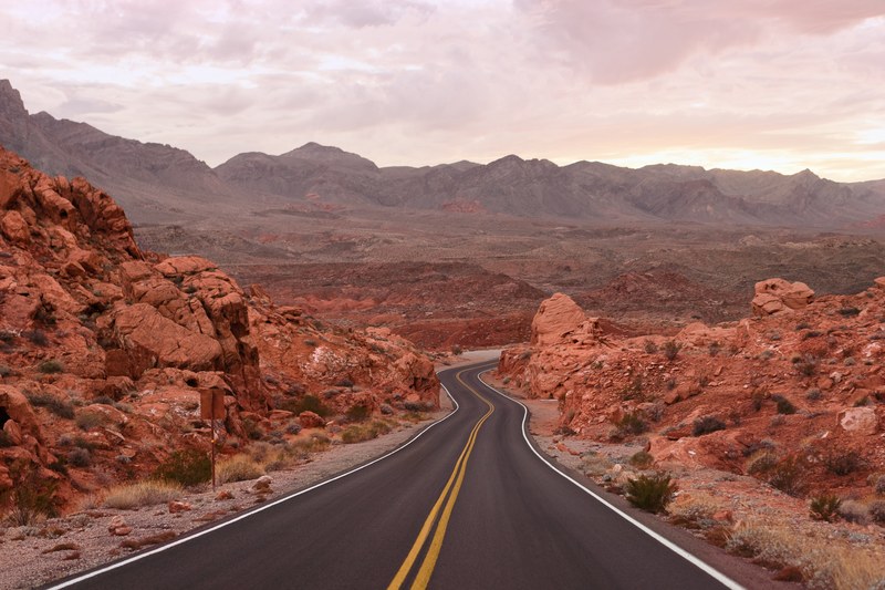 open road winds through red rocky mountains in a desert, mars one 4k