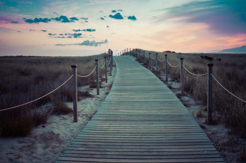 wooden boardwalk with rope fence through the grass field after the sunset, staying up all night to watch the sunrise 4k