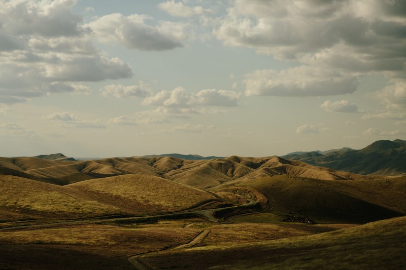 a dirt road running through a hilly landscape, road through the hills 4k