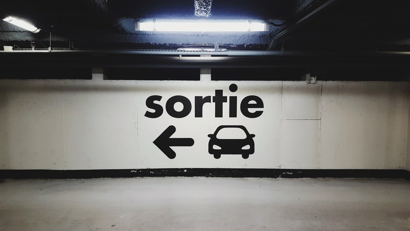 french exit sign and light in urban underground car park parking du centre commercial la part dieu, french exit sign in car park 4k