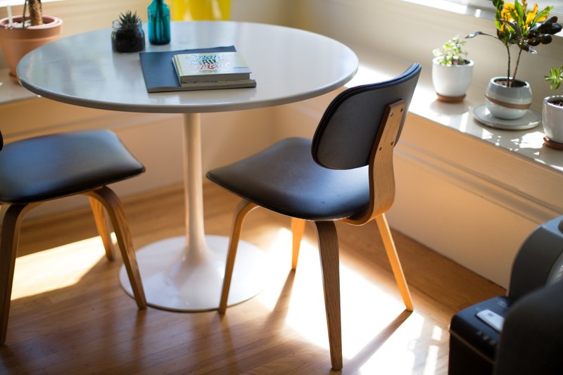 small chairs next to a round table at a corner of a bright room, round table in a bright room 4k