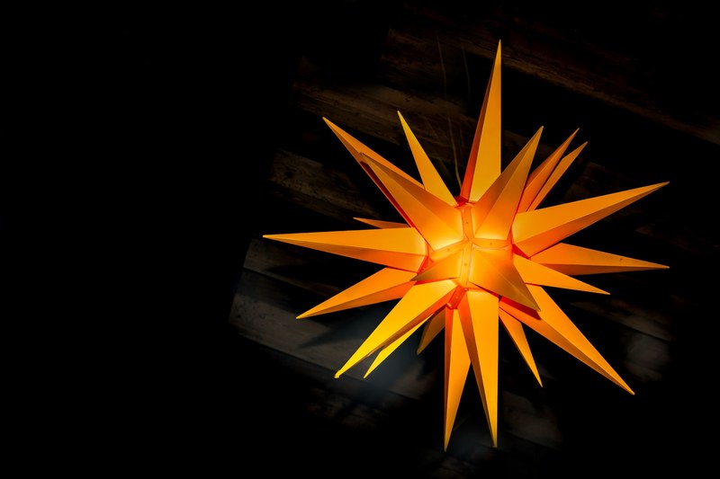 an orange decoration in the shape of multi pointed star hanging from a ceiling, orange star decoration 4k