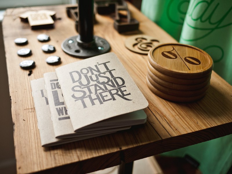 notebooks with a dont just stand there cover on a table next to various trinkets, notebooks and trinkets 4k