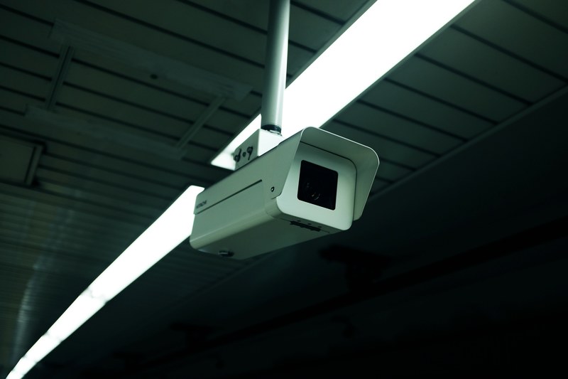 white surveillance camera monitoring a dark space with lined ceilings and overhead lights, ceiling surveillance camera 4k