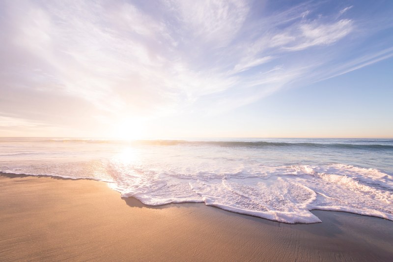 ocean waves with foam washing on a sand beach on sunset in san diego, sunrise above a sandy beach 4k