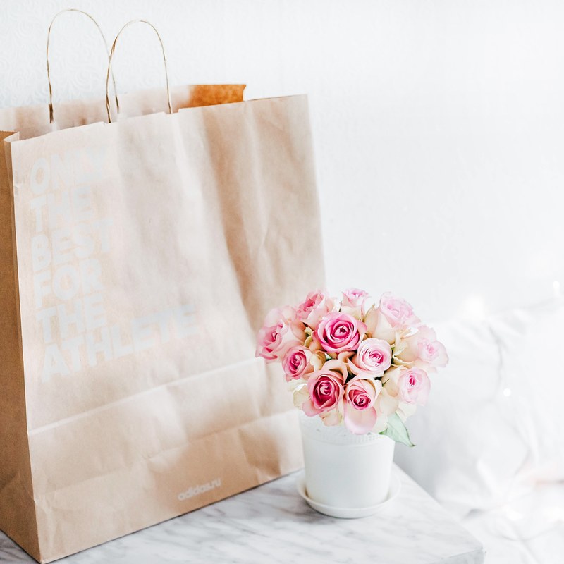 a cup of flowers next to a gift bag, _flowers 4k