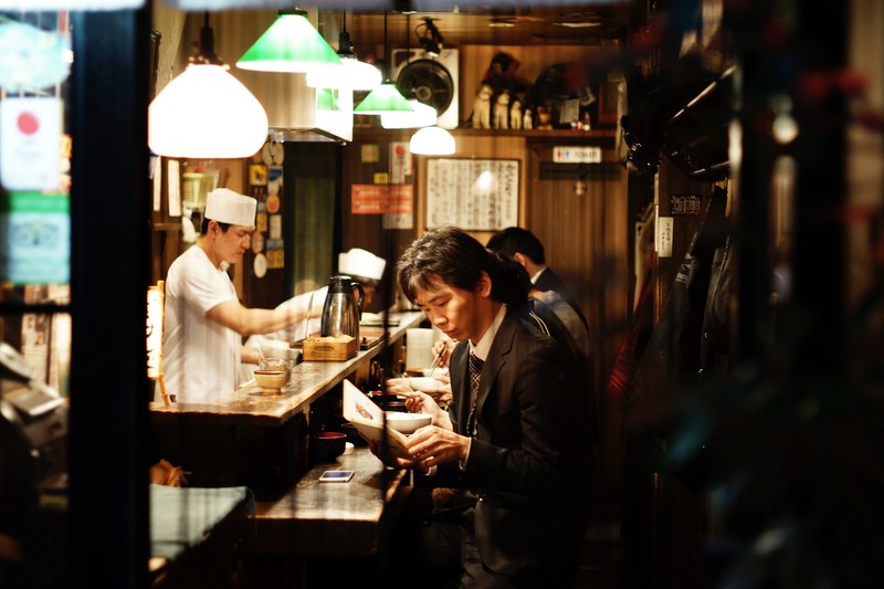 a man sitting at the counter at a ramen restaurant in shinjuku, restaurant in japan 4k