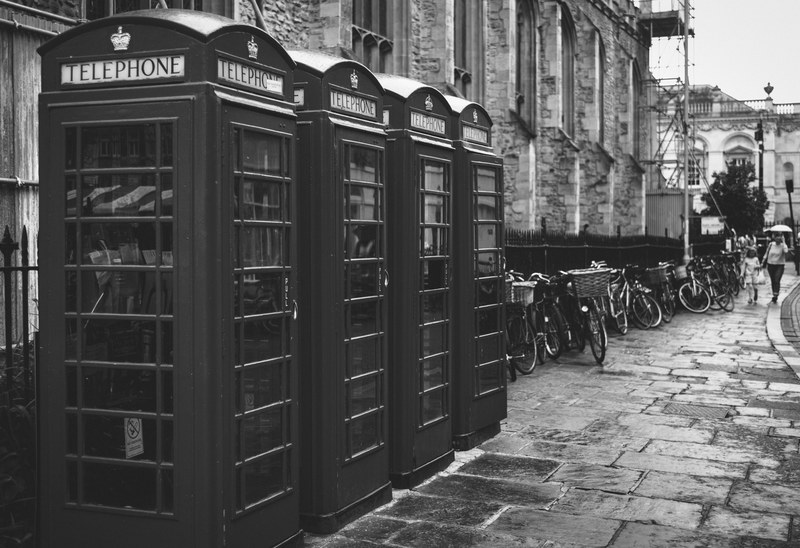 black and white shot of traditional red telephone boxes on street with bikes in cambridge, phoneboxes by the street 4k