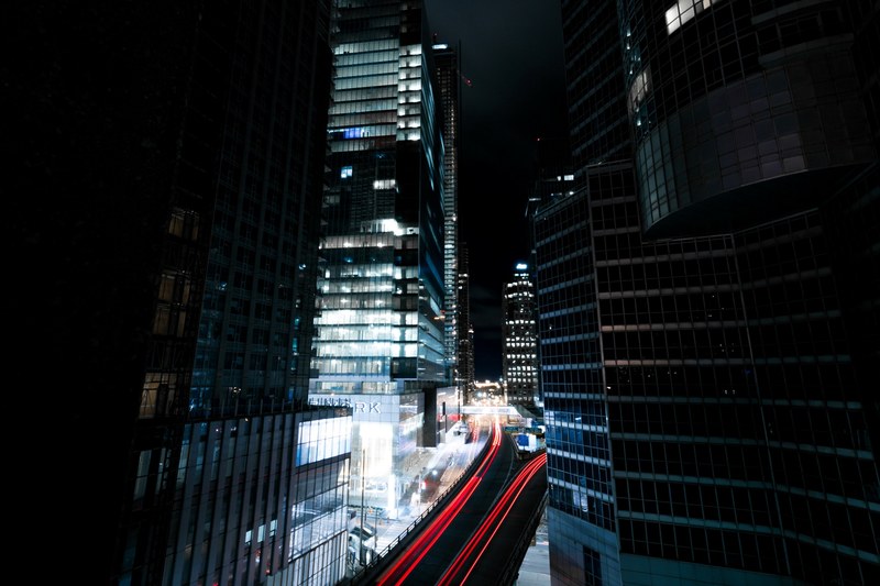 a dark photo of a dimly lit urban building with traffic light trails below, roads end 4k