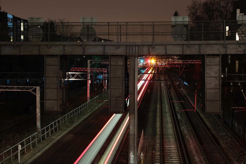 a long exposure shot with light trails on an urban railroad track under an overpass at night, light trails under an overpass 4k