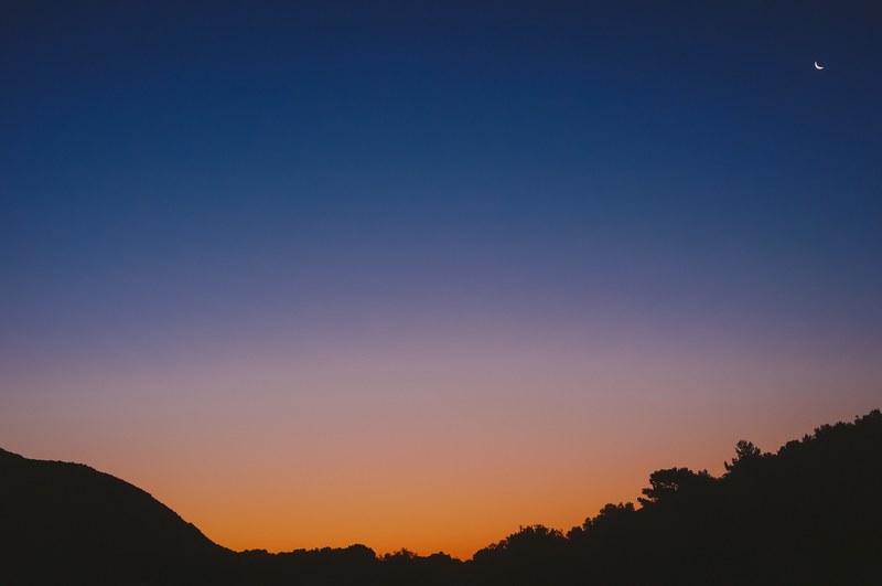 small crescent moon rises in the twilight glow of the sky, small cresent moon twilight 4k