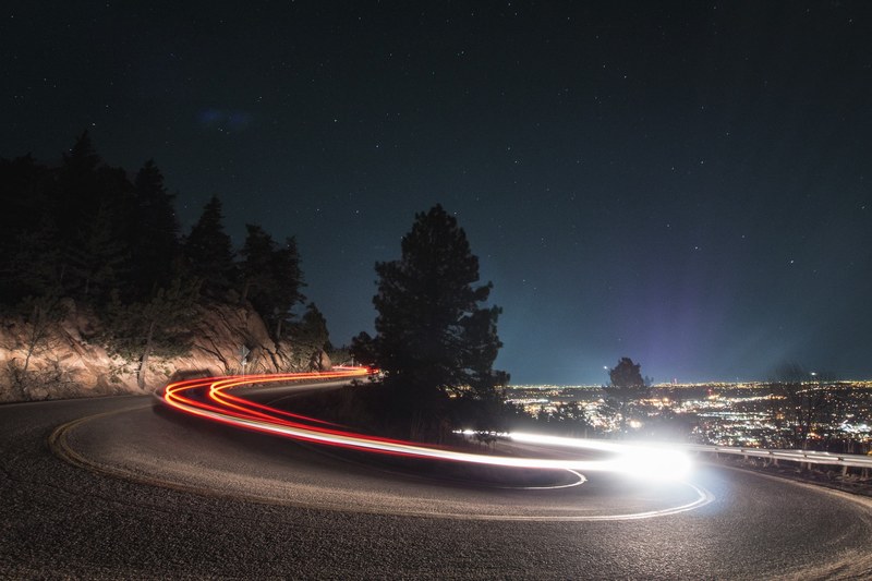 a slow shutter shot of a curved road in boulder with fast driving car light trails, tokyo drift 4k