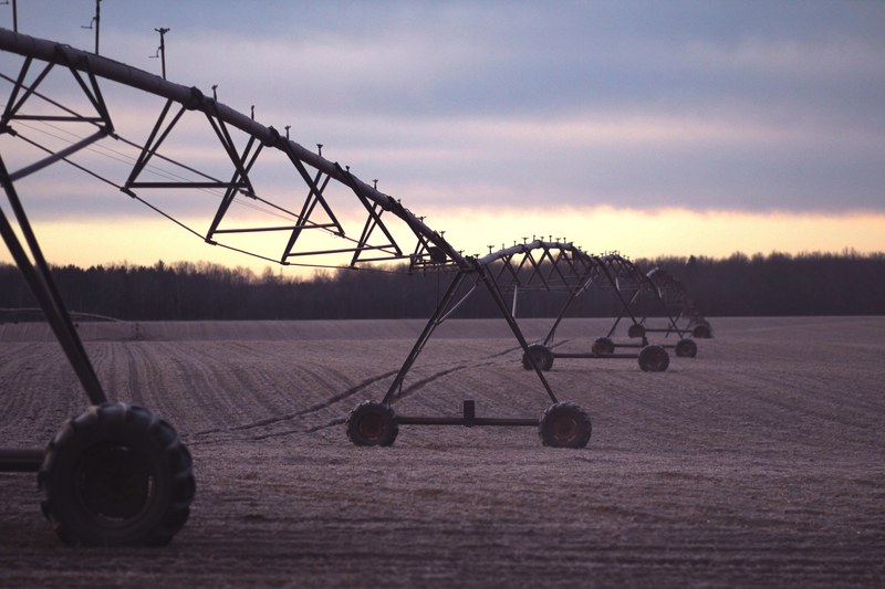 a long pivot irrigation system in a plowed field, long sprinkler in the field 4k