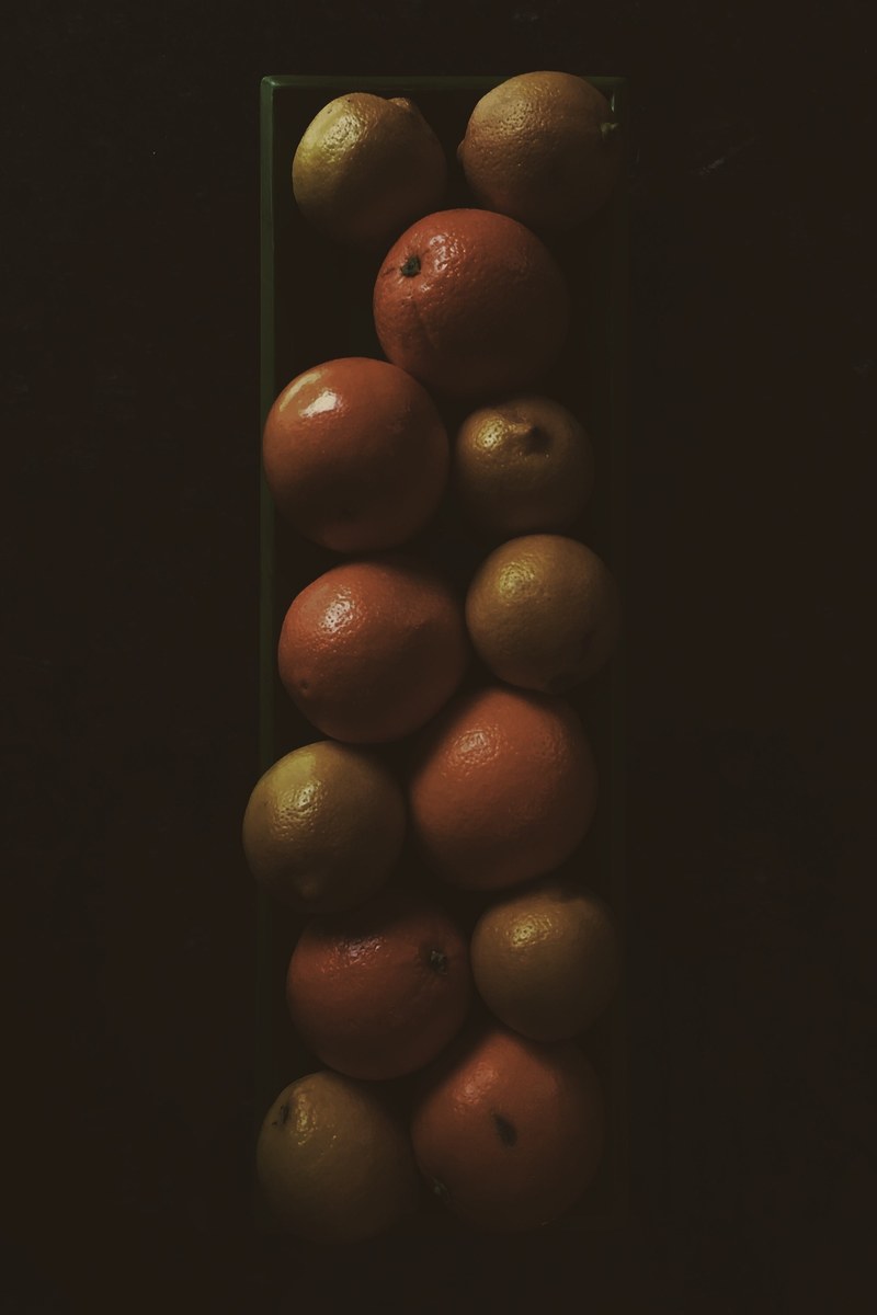 stack of lemons oranges and citrus fruit in a glass vase, fruit on display 4k