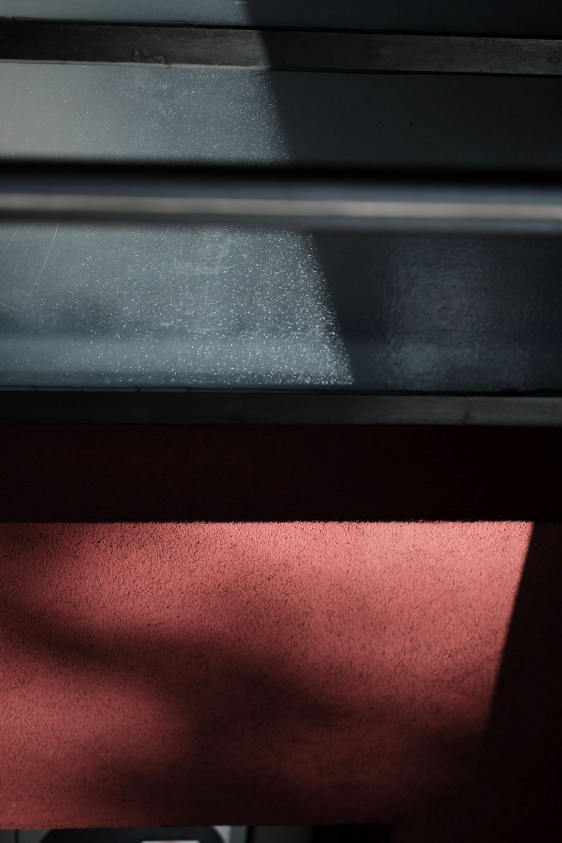 sunlight on a black steel surface above a rough red wall, sunlight on black and red 4k