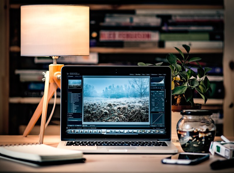 a macbook with photo editing software on a busy desk, photo editing laptop 4k