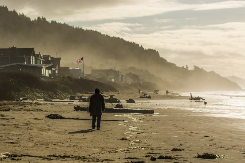 person walking on the windy sand beach by the houses with american flag, person walking on windy beach 4k