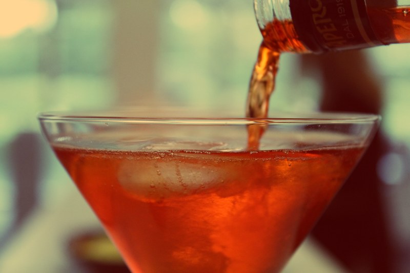 the macro view of the pouring of an alcoholic drink in a glass cup with ice cubes in it, pouring of an alcoholic drink 4k