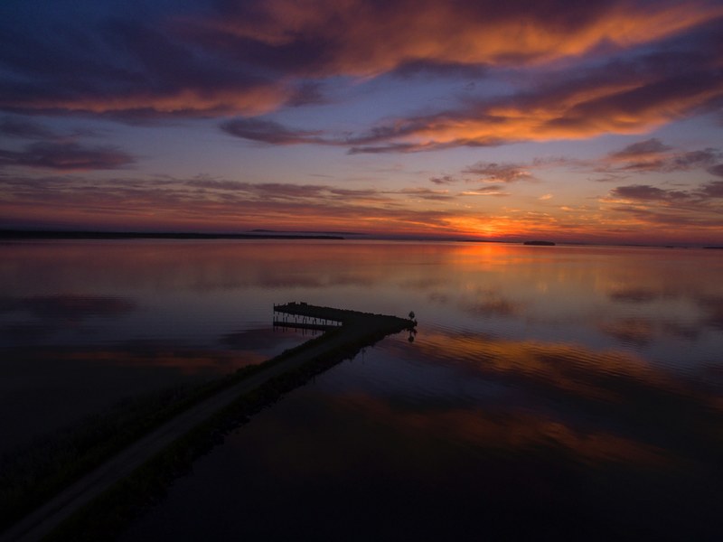 view of a coastline in michigan with a colorful sunrise at the horizon, evening view of the lake 4k