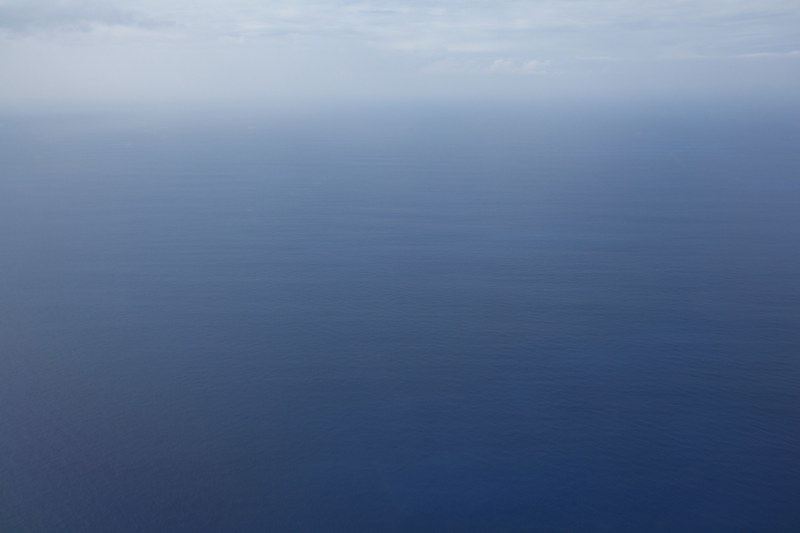 still ocean waters disappear into the blue horizon covered in clouds, endless blue waters 4k
