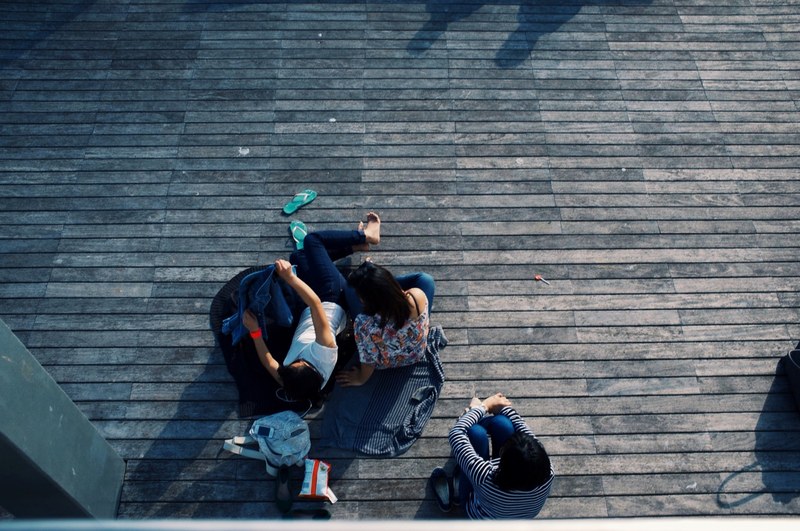 a group of people laying down on a deck covering themselves with sweaters, couple relaxing on a blanket 4k