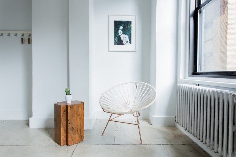 white chair and wood table sit inside a white room next to window, white room decoration 4k