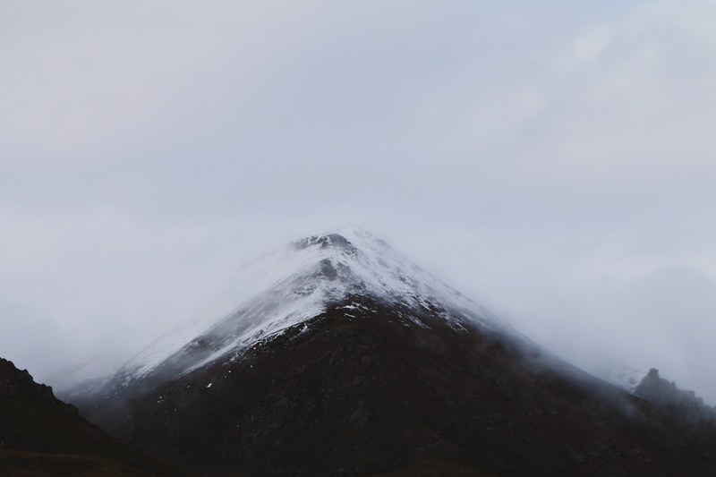snowy summit of a mountain covered by fog and clouds, snowy summit in fog 4k