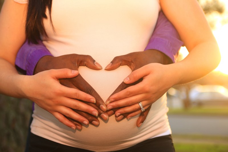mans hands wrap around the pregnant belly of his girlfriend, world in our hands 4k