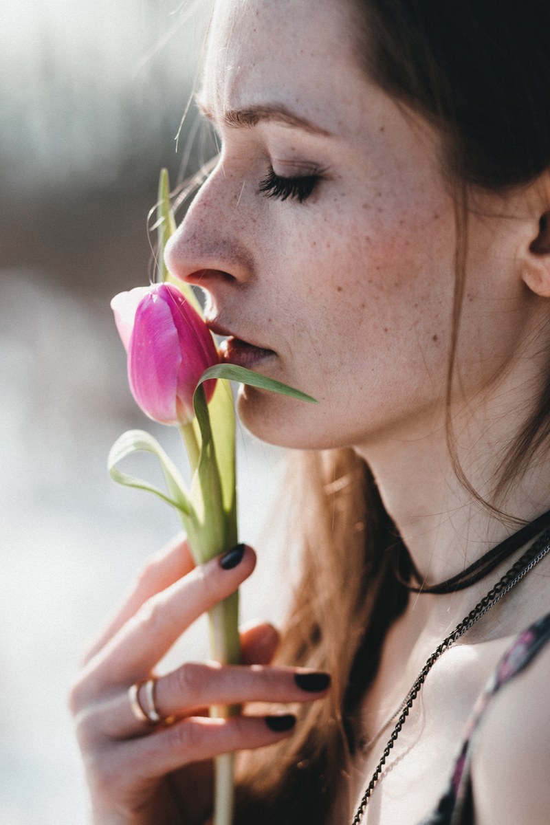a woman holding up a pink tulip to her lips, kissing a pink tulip 4k