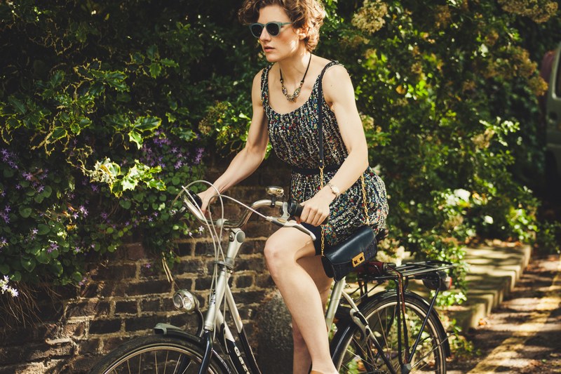 woman wearing gold watch dress and purse and riding vintage bike through london, woman wearing watch on bike 4k