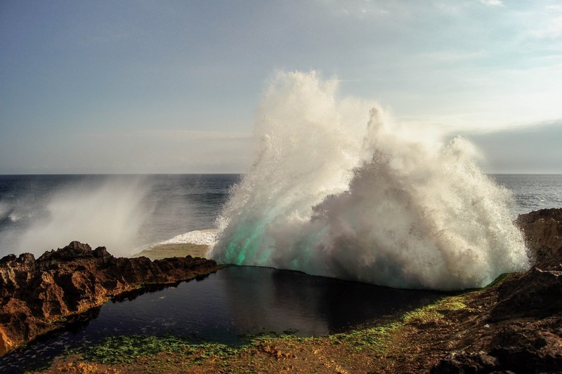 an ocean wave hitting rocks and creating spray on the coast, ocean spray 4k