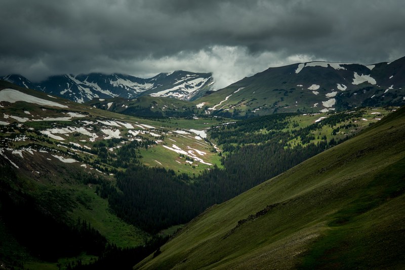patches of snow in a wooded mountain valley on a cloudy day, snow in a mountain valley 4k