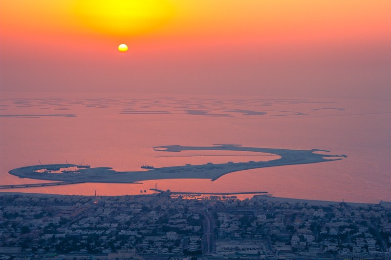 an abstract shaped artificial island on a body of water during sunrise, artificial island at dusk 4k