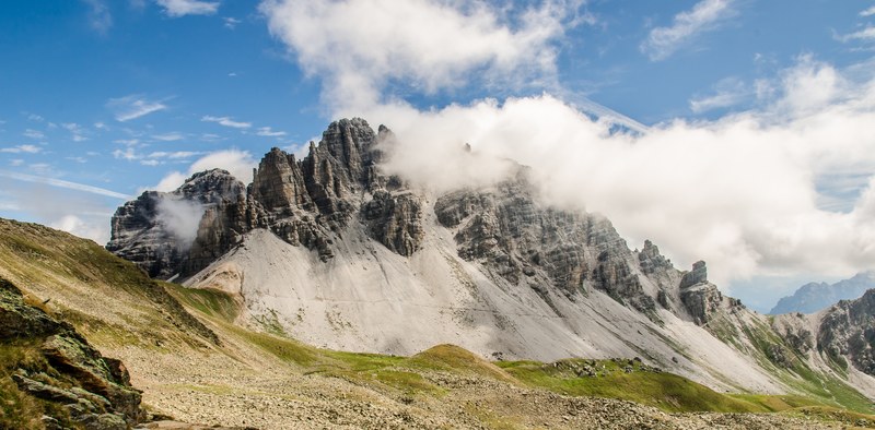 clouds cover rocky mountain peaks near a lush green pasture, peaks and pastures 4k